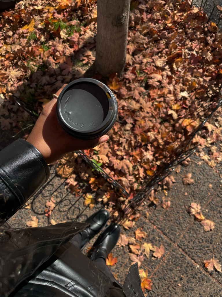 standing over fall  orange,brown and red leaves whine holding a coffee cup